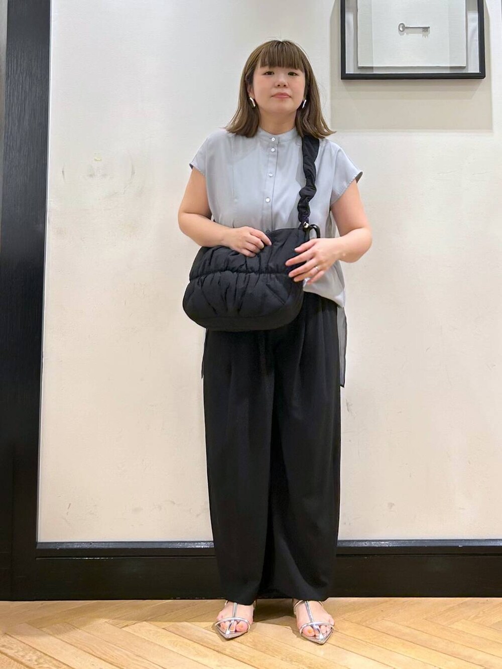 シルバー系のサンダル、ブラック系のスラックス、ブラック系のショルダーバッグを着用したレディースの夏コーディネートの3枚目の写真