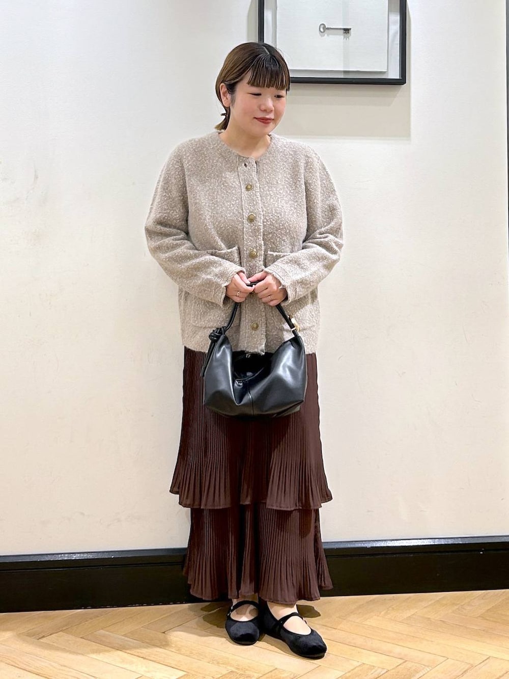 ブラウン系のスカート、ベージュ系のカーディガン/ボレロ、ブラック系のバレエシューズを着用したレディースの秋コーディネートの2枚目の写真