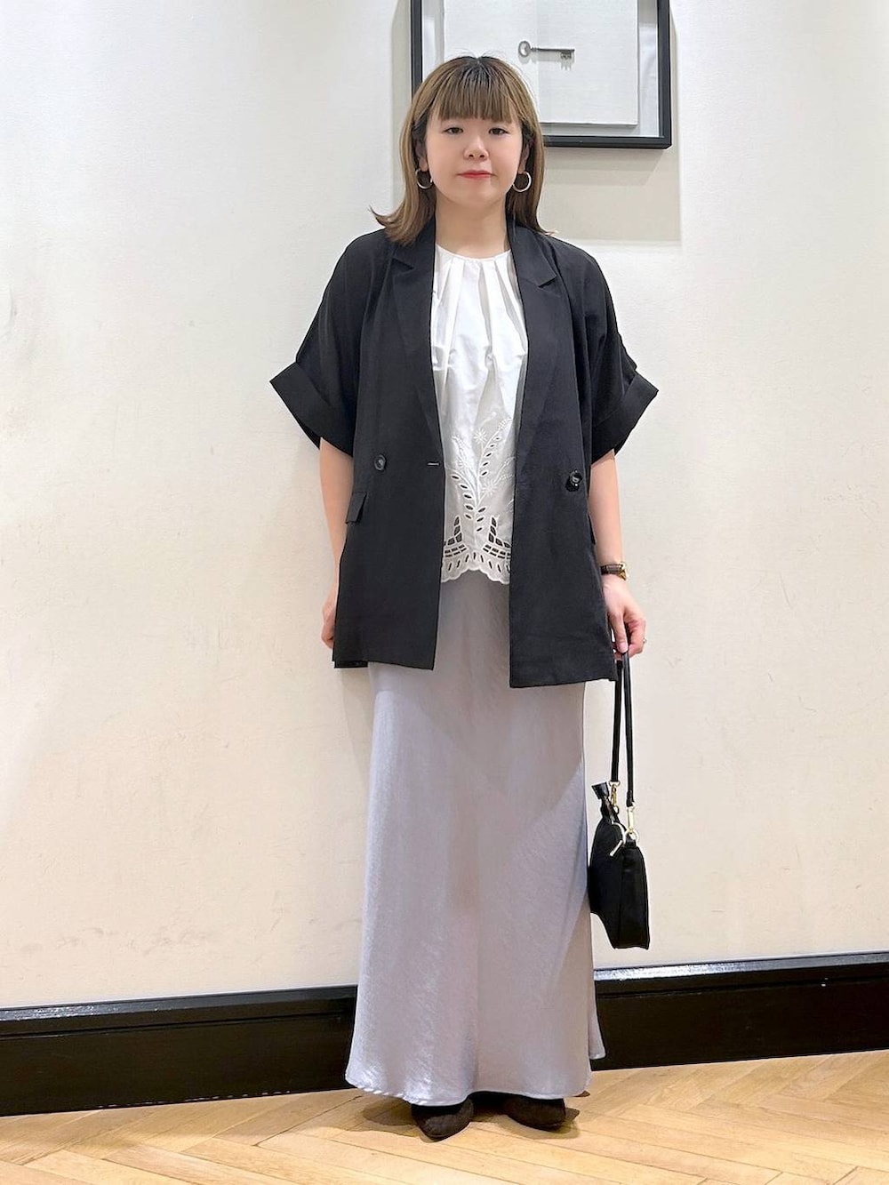 ブルー系のスカート、ブラウン系のパンプス、ホワイト系のシャツ/ブラウスを着用したレディースの夏コーディネートの3枚目の写真