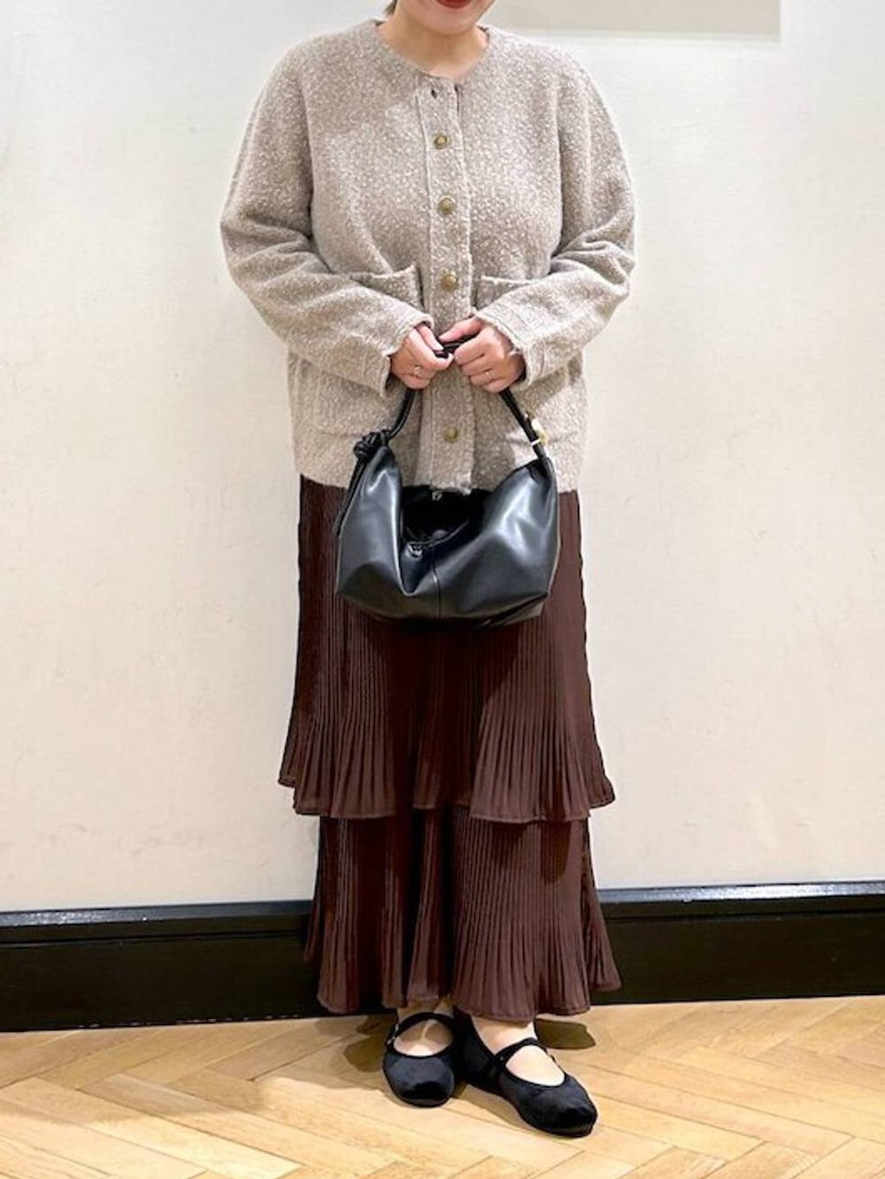 ブラウン系のスカート、ベージュ系のカーディガン/ボレロ、ブラック系のバレエシューズを着用したレディースの秋コーディネートの9枚目の写真