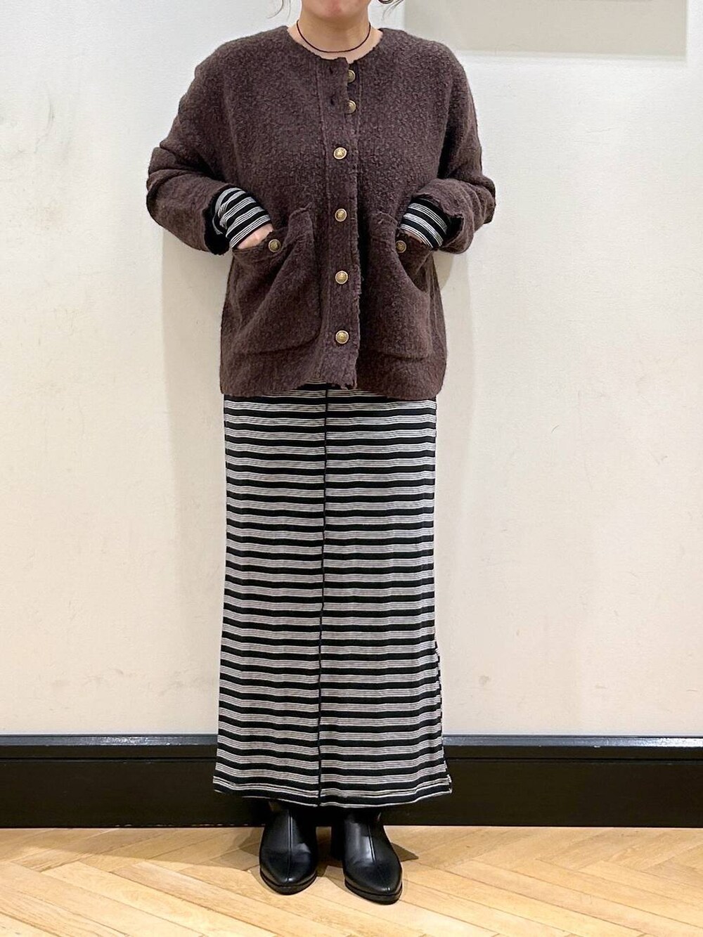 ブラック系のブーツ、ブラック系のワンピース、ブラウン系のカーディガン/ボレロを着用したレディースの秋コーディネートの2枚目の写真