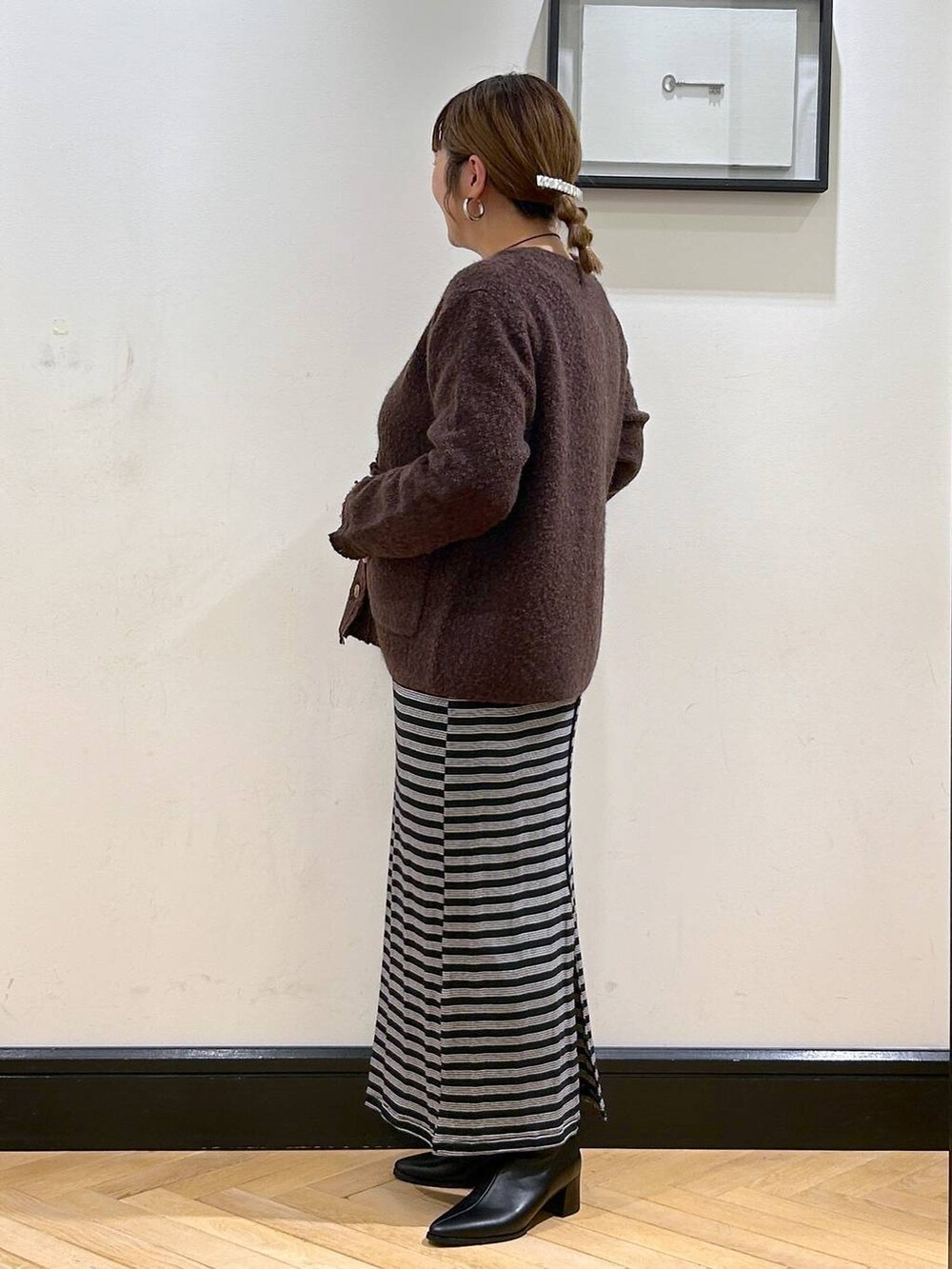 ブラック系のブーツ、ブラック系のワンピース、ブラウン系のカーディガン/ボレロを着用したレディースの秋コーディネートの3枚目の写真