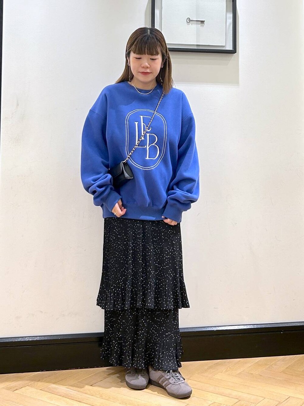 グレー系のスカート、グレー系のスニーカー、ブルー系のスウェットを着用したレディースの秋コーディネートの4枚目の写真