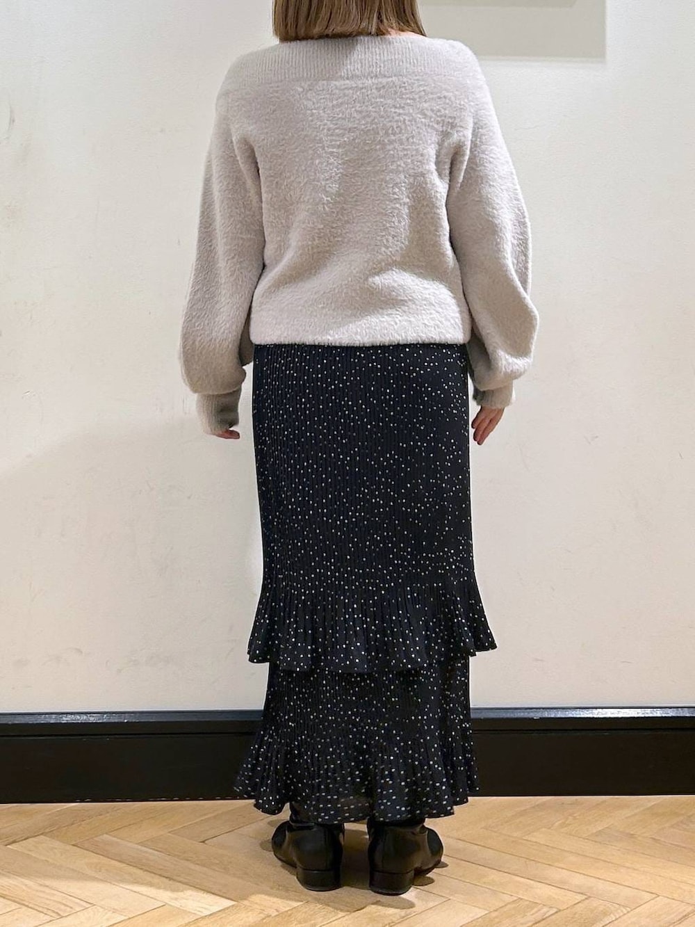 グレー系のスカート、ブラック系のブーツ、グレー系のニット/セーターを着用したレディースの冬コーディネートの4枚目の写真