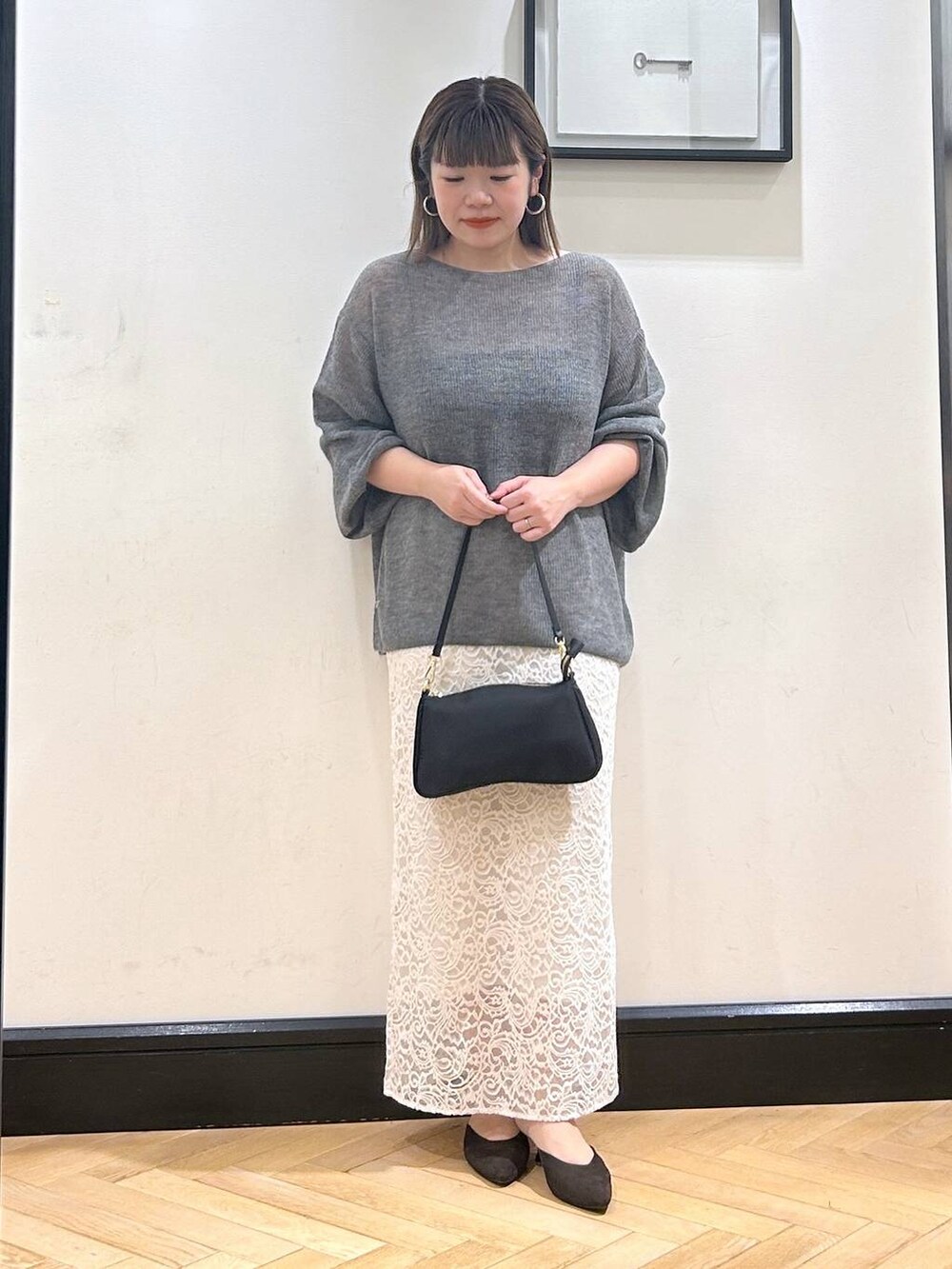 グレー系のニット/セーター、ブラウン系のパンプス、ホワイト系のスカートを着用したレディースの秋コーディネートの3枚目の写真
