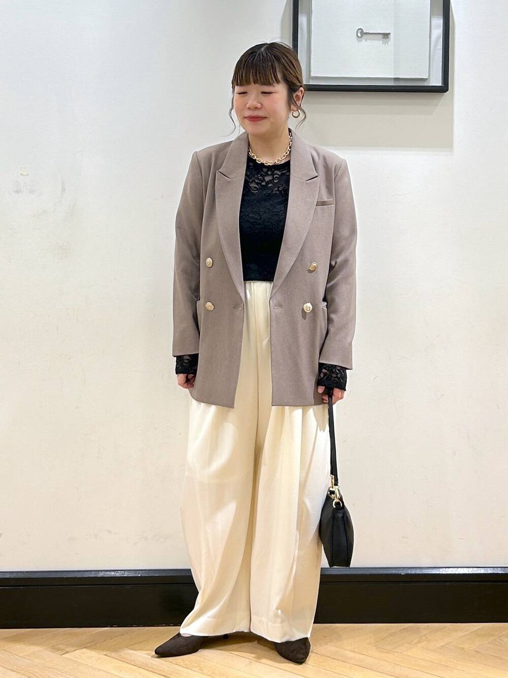 ホワイト系のスラックス、ブラウン系のパンプス、ブラック系のショルダーバッグを着用したレディースの秋コーディネートの3枚目の写真