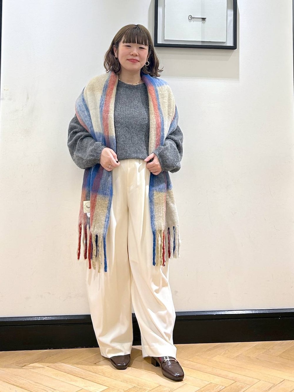 ホワイト系のスラックス、ブラウン系のローファー、グレー系のニット/セーターを着用したレディースの秋コーディネートの4枚目の写真