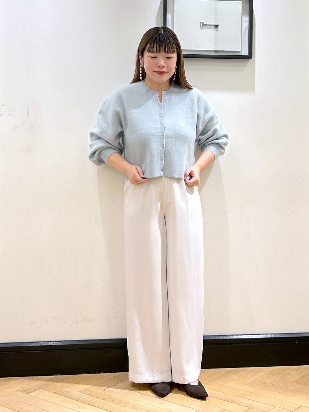 グリーン系のカーディガン/ボレロ、ホワイト系のスラックス、ブラウン系のパンプスを着用したレディースの秋コーディネートの2枚目の写真