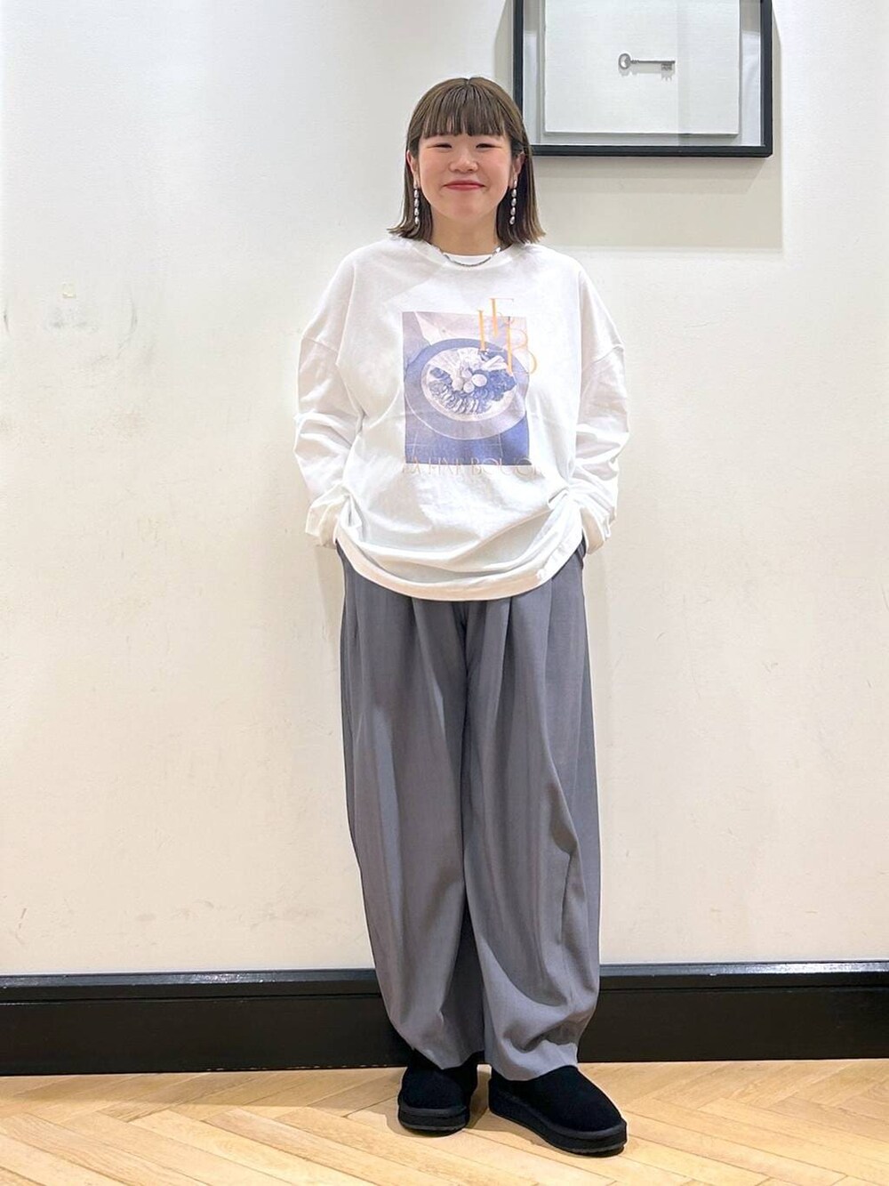 グレー系のスラックス、ホワイト系のTシャツ/カットソー、ブラック系のスリッポンを着用したレディースの秋コーディネートの2枚目の写真