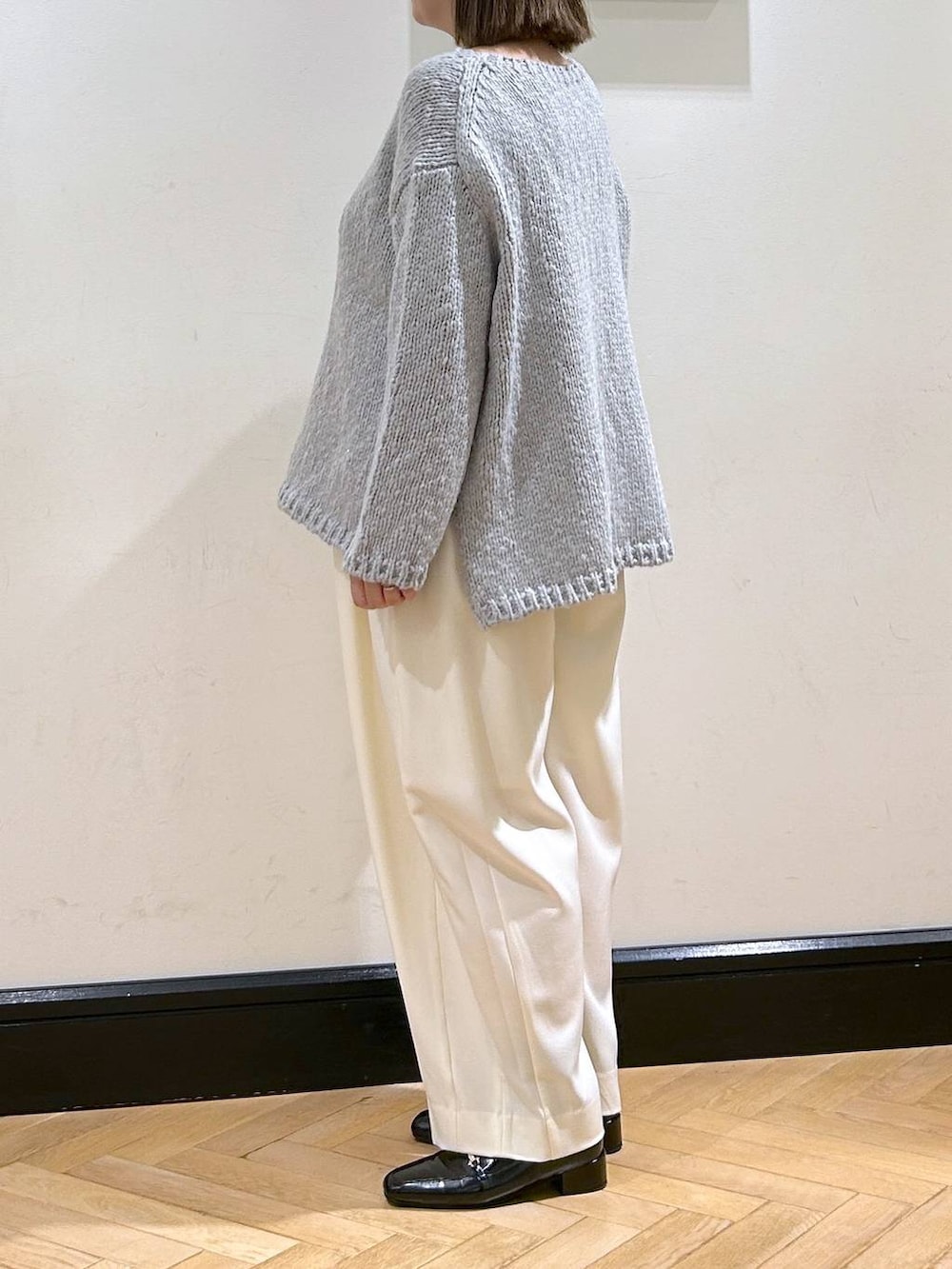 ホワイト系のスラックス、ブラック系のローファー、グレー系のニット/セーターを着用したレディースの秋コーディネートの5枚目の写真