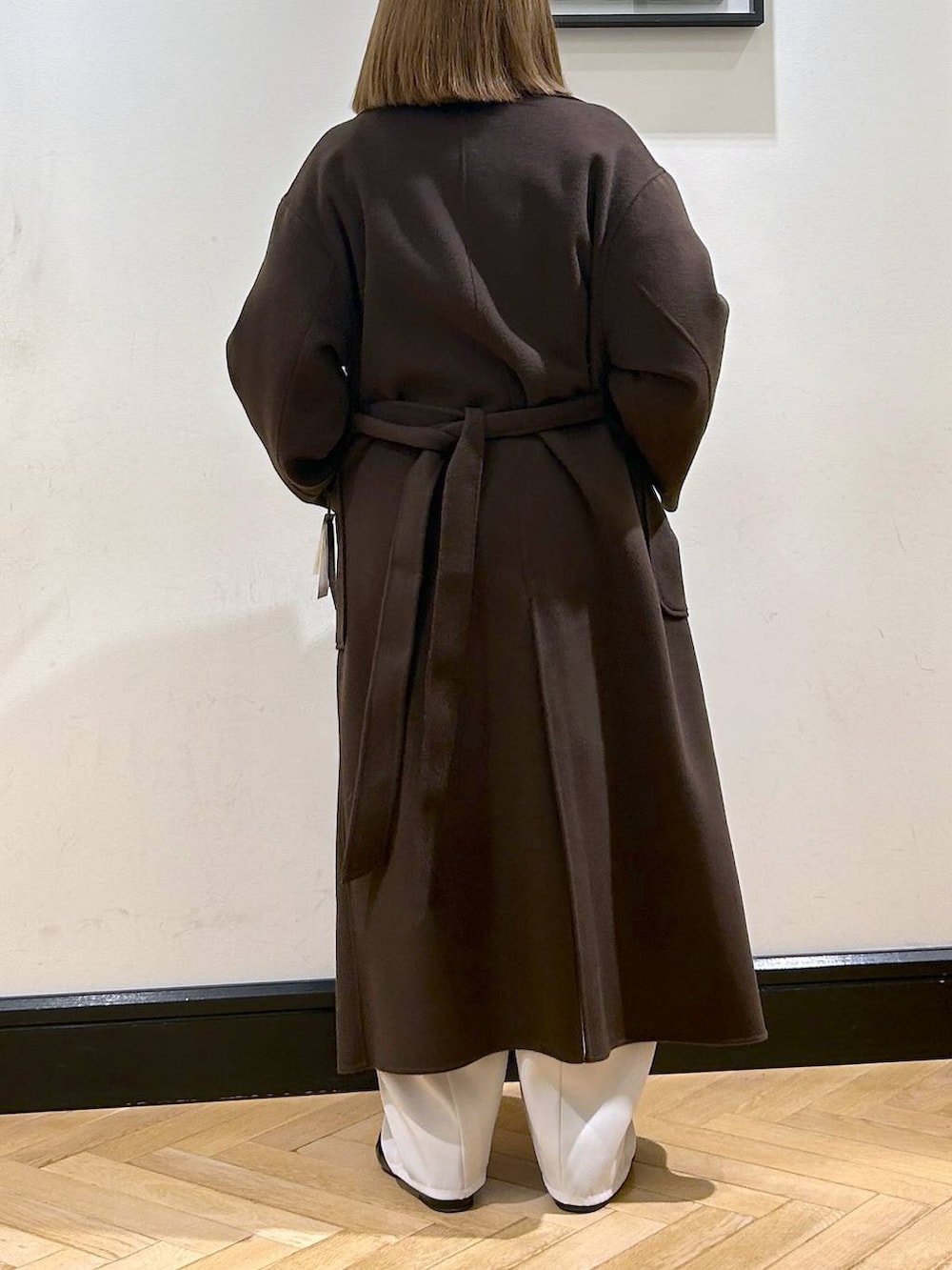 ブラウン系のステンカラーコート、ブラック系のローファー、ブルー系のニット/セーターを着用したレディースの秋コーディネートの6枚目の写真