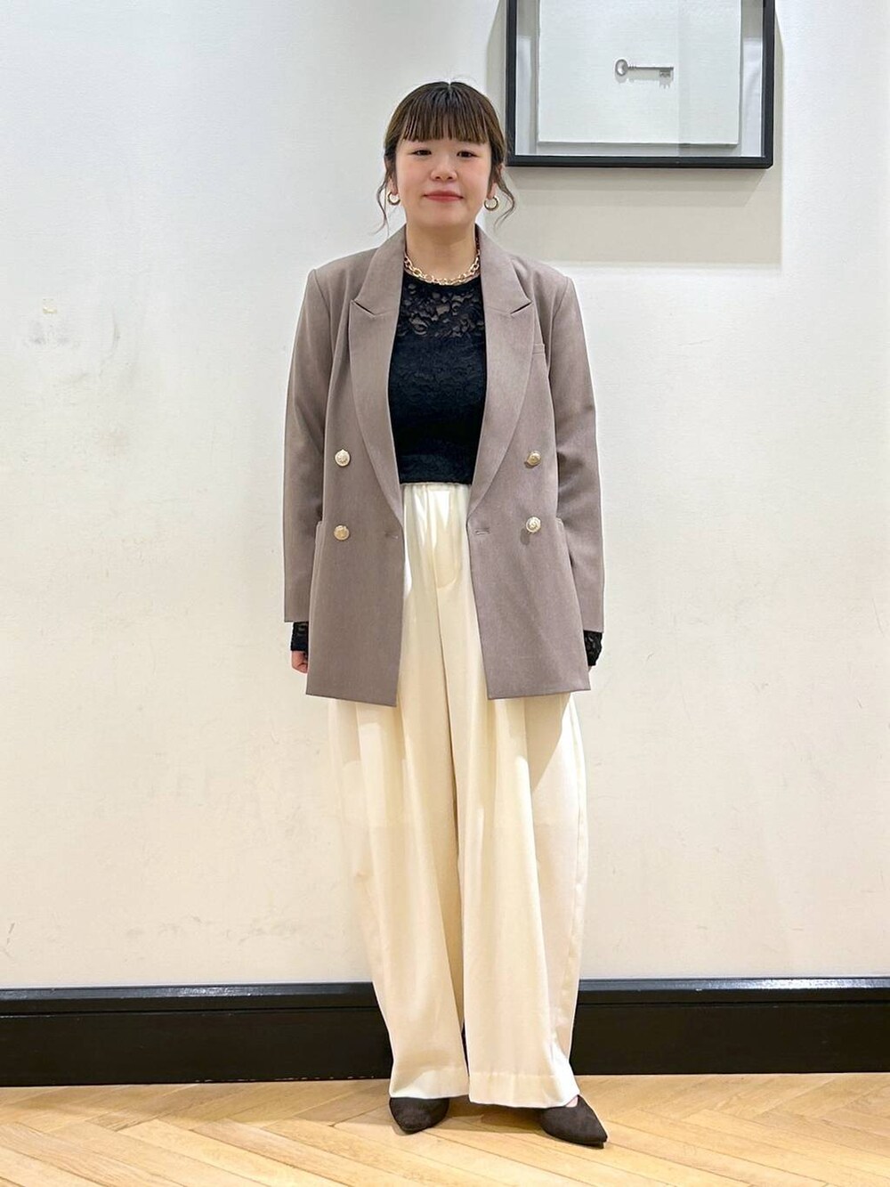 ホワイト系のスラックス、ブラウン系のパンプス、ブラック系のショルダーバッグを着用したレディースの秋コーディネートの6枚目の写真