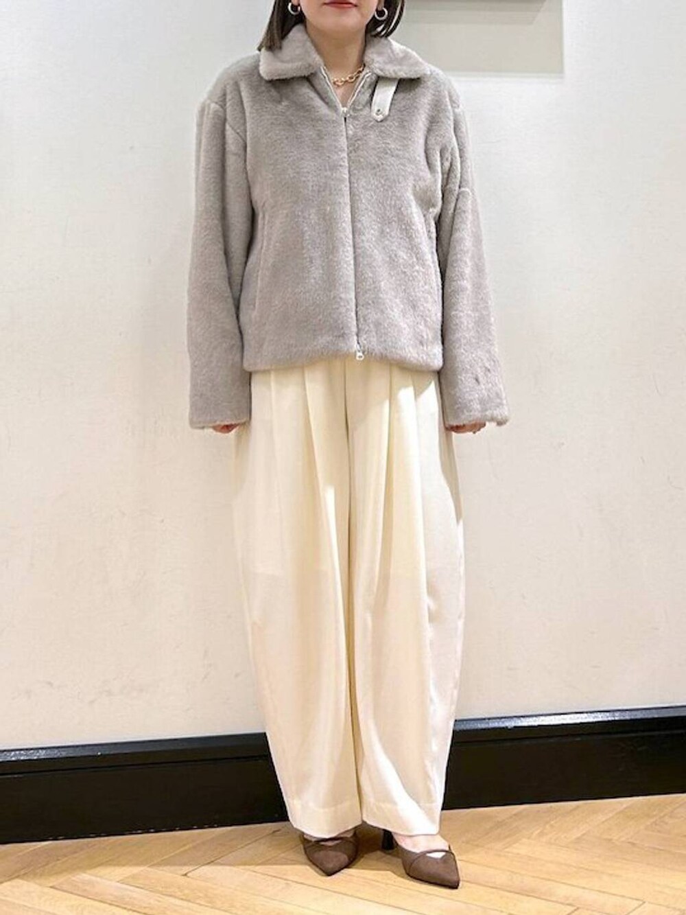 ホワイト系のスラックス、グレー系のその他アウター、ゴールド系のネックレスを着用したレディースの秋コーディネートの3枚目の写真