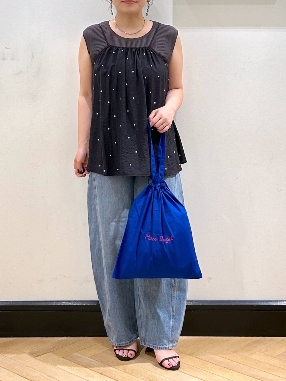 ブルー系のデニムパンツ、ブラウン系のサンダル、グレー系のタンクトップを着用したレディースの夏コーディネートの8枚目の写真