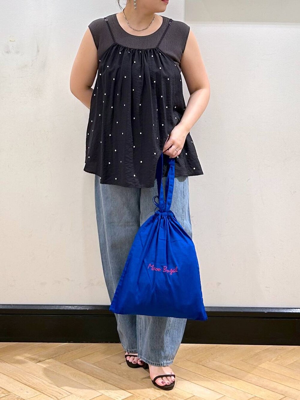 ブルー系のデニムパンツ、ブラウン系のサンダル、グレー系のタンクトップを着用したレディースの夏コーディネートの2枚目の写真