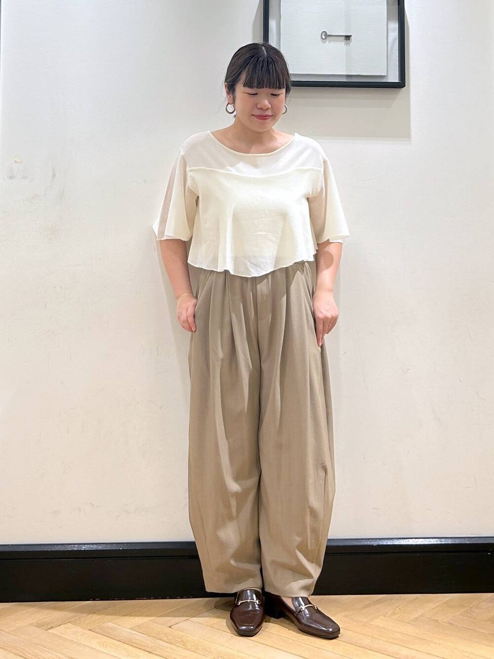 ベージュ系のスラックス、ブラウン系のローファー、ホワイト系のニット/セーターを着用したレディースの夏コーディネートの3枚目の写真