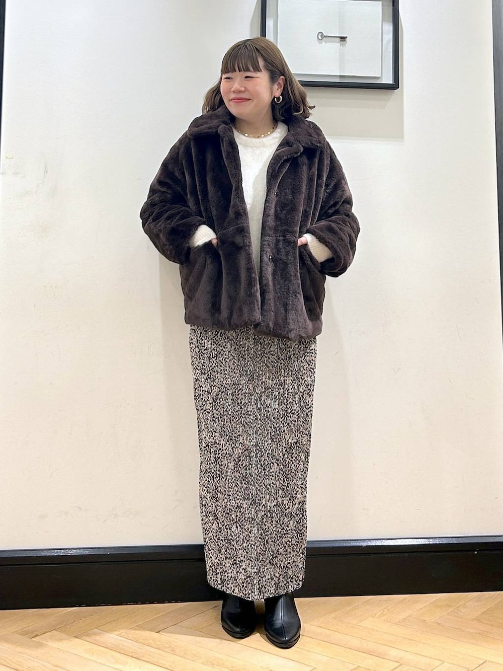 ブラック系のブーツ、ブラウン系のその他アウター、ホワイト系のカーディガン/ボレロを着用したレディースの秋コーディネートの2枚目の写真