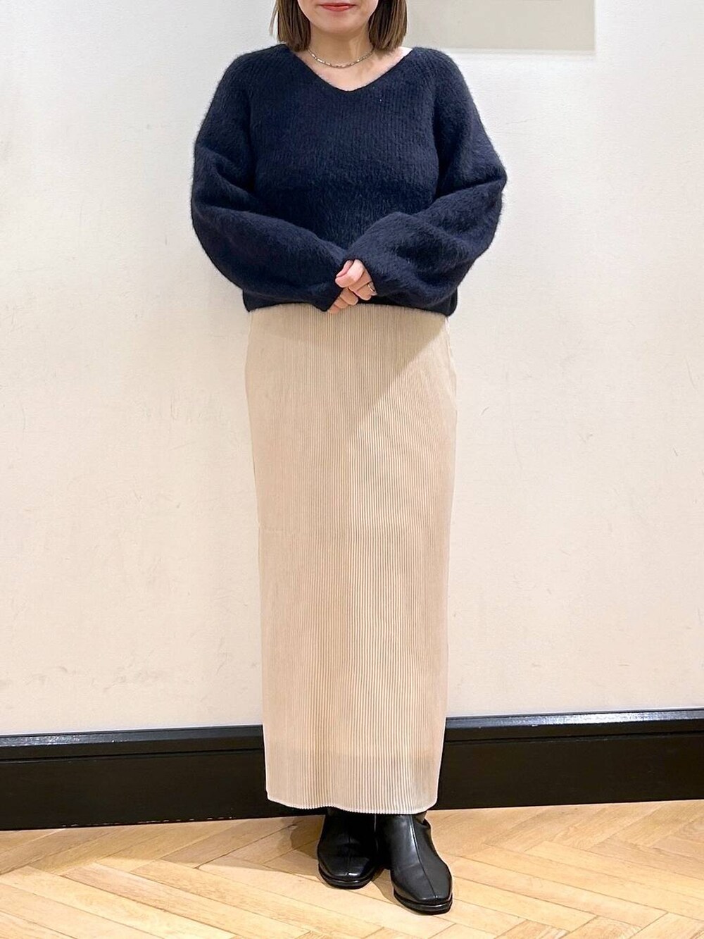 ブルー系のニット/セーター、ホワイト系のスカート、ブラック系のブーツを着用したレディースの秋コーディネートの5枚目の写真
