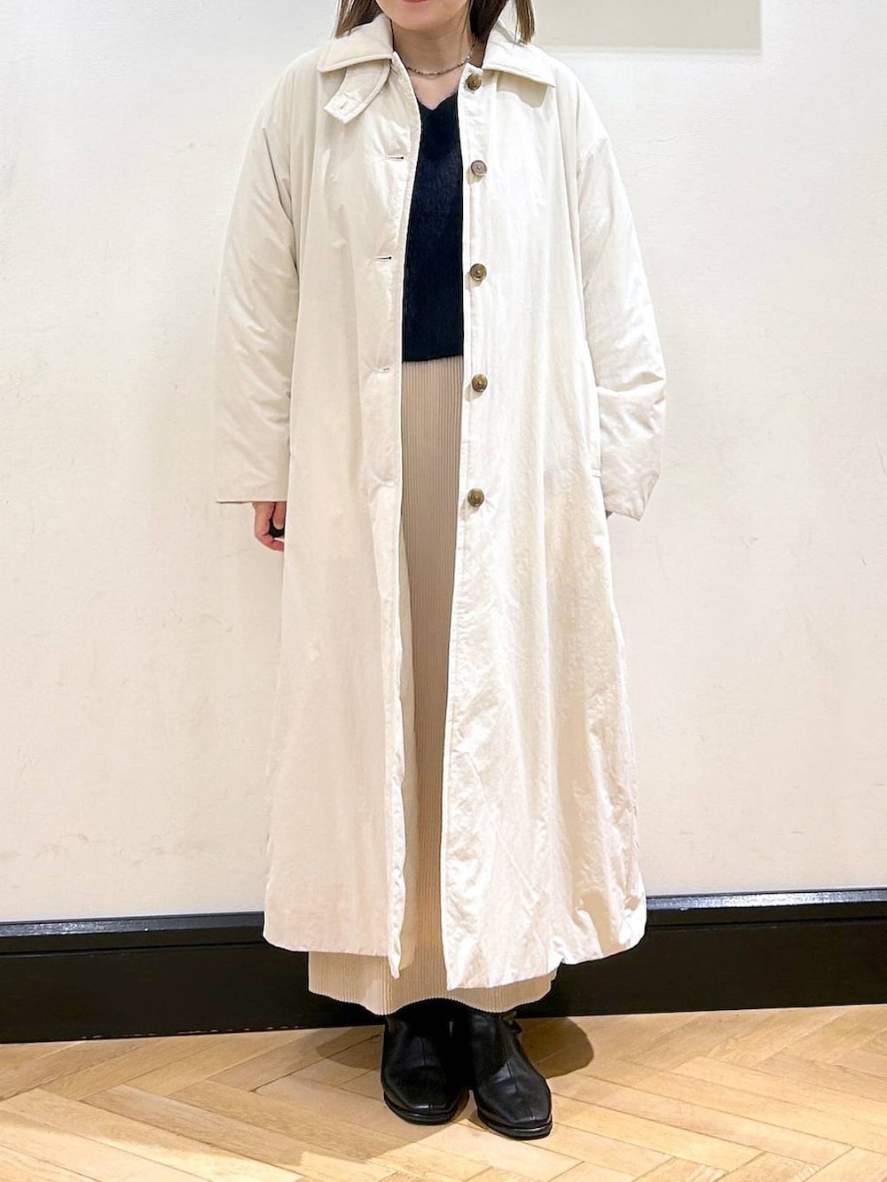 ブルー系のニット/セーター、ホワイト系のスカート、ホワイト系のダウンジャケット/コートを着用したレディースの秋コーディネートの2枚目の写真