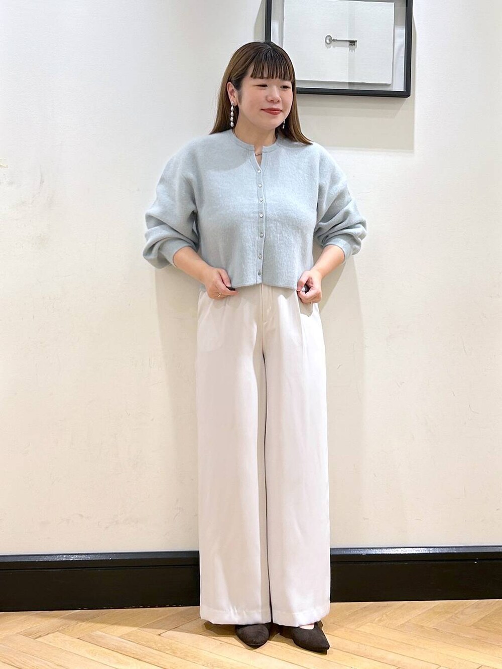 グリーン系のカーディガン/ボレロ、ホワイト系のスラックス、ブラウン系のパンプスを着用したレディースの秋コーディネートの3枚目の写真