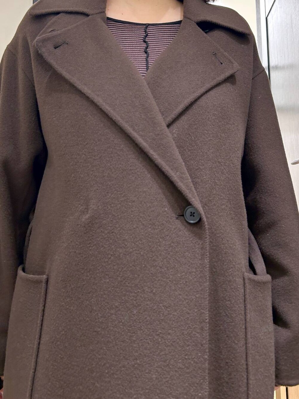 ブラウン系のステンカラーコート、ブラック系のスニーカー、ブラウン系のワンピースを着用したレディースの秋コーディネートの10枚目の写真