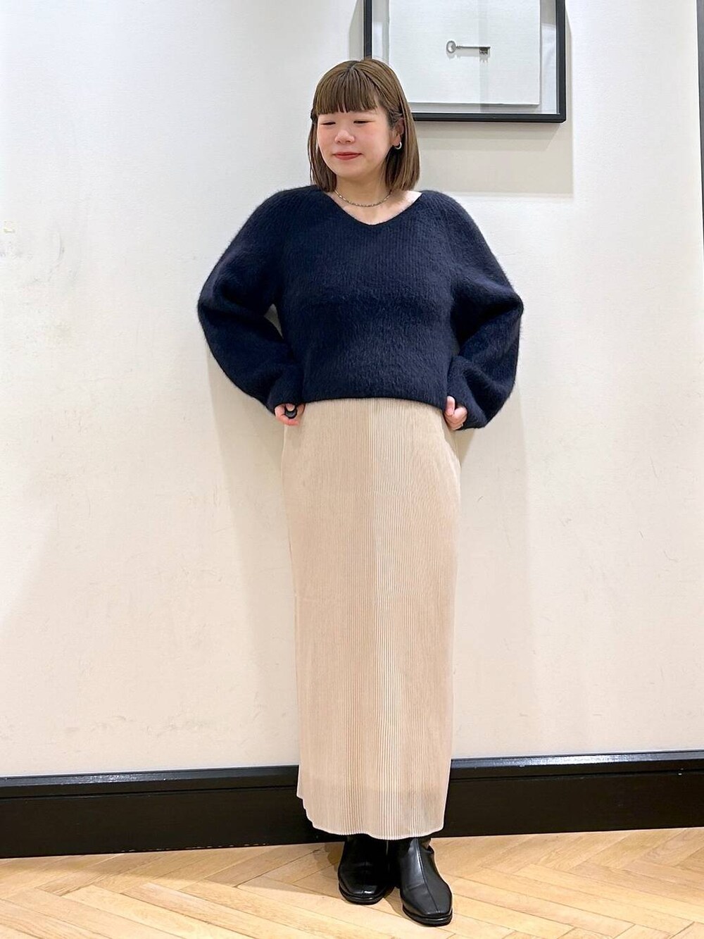 ブルー系のニット/セーター、ホワイト系のスカート、ブラック系のブーツを着用したレディースの秋コーディネートの3枚目の写真