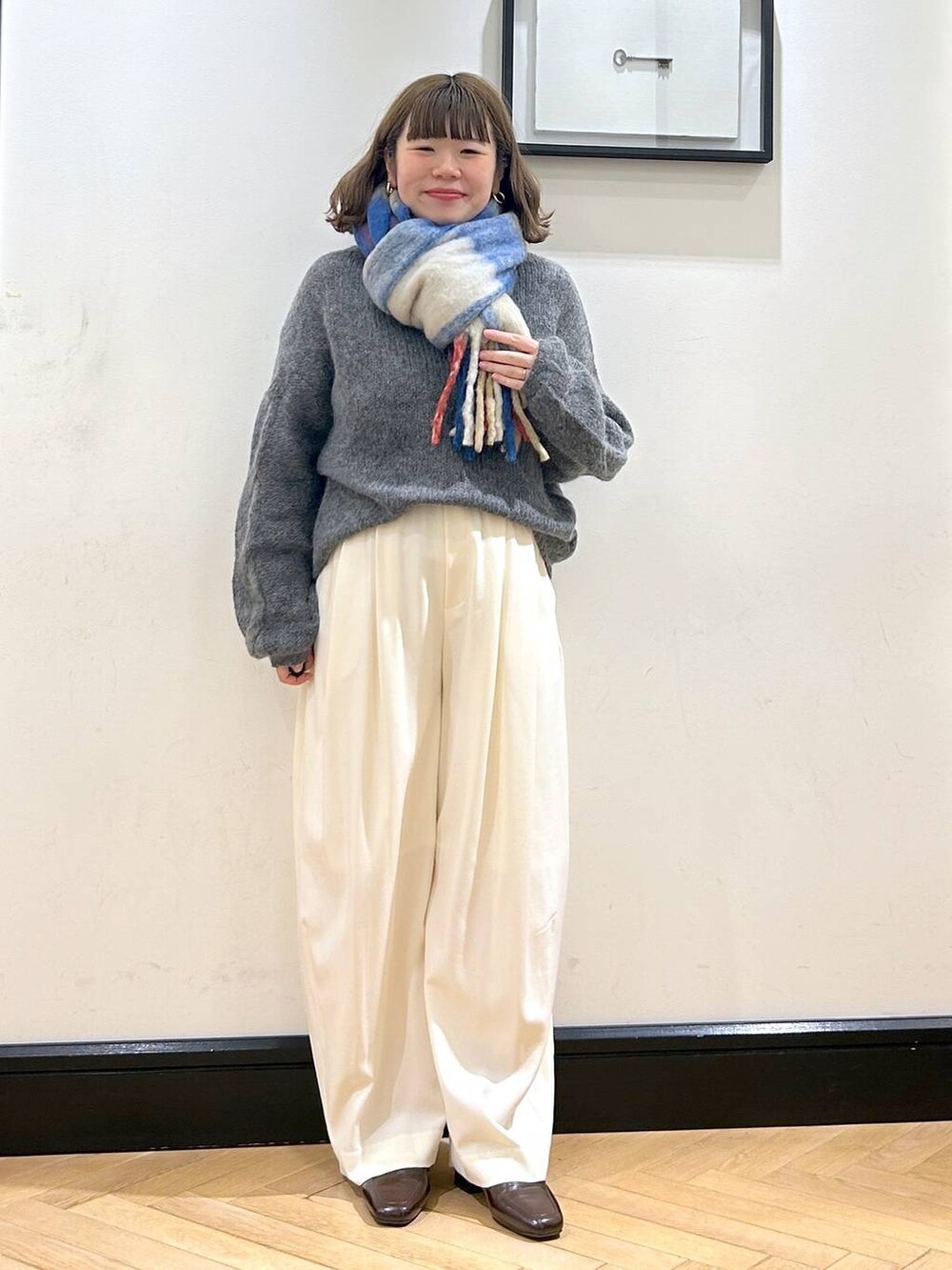 ホワイト系のスラックス、ブラウン系のローファー、グレー系のニット/セーターを着用したレディースの秋コーディネートの2枚目の写真