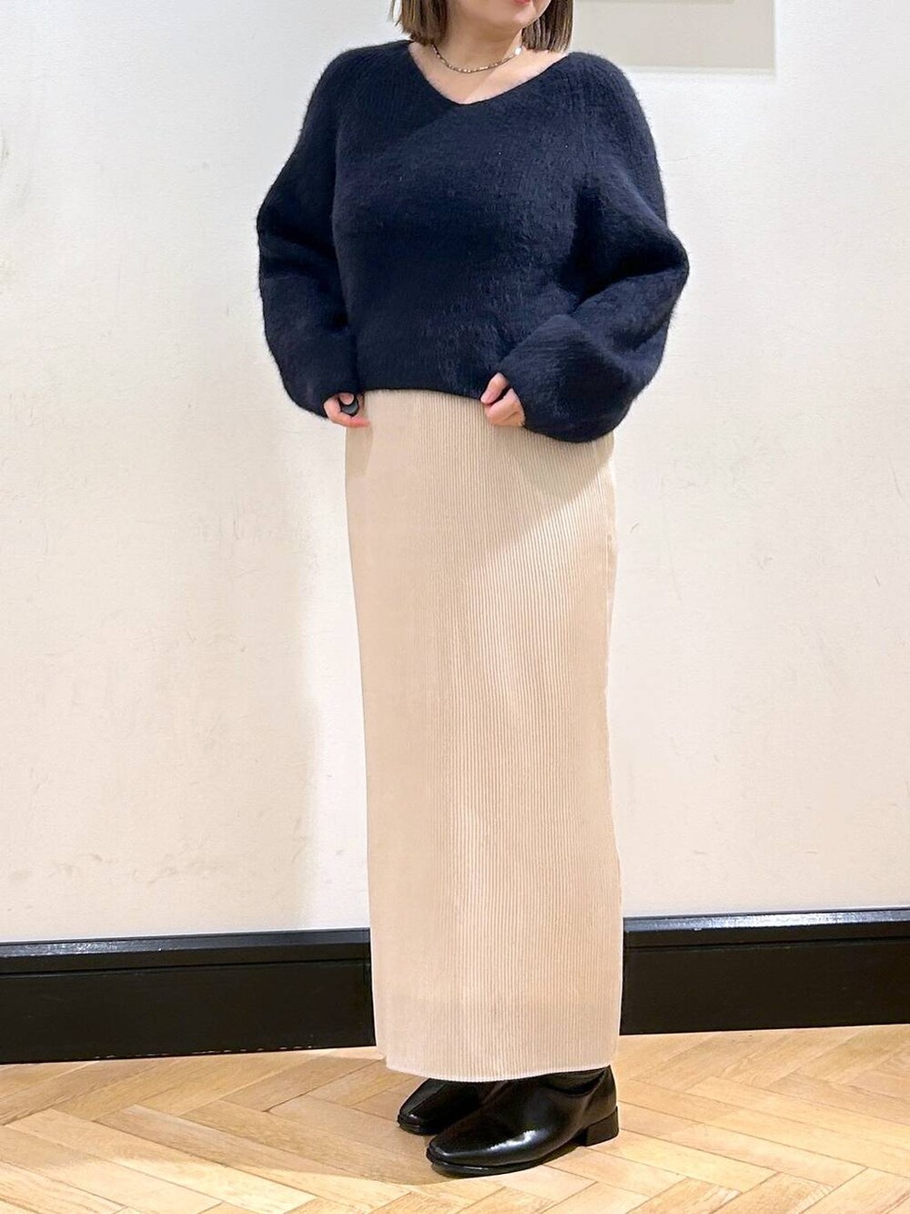 ブルー系のニット/セーター、ホワイト系のスカート、ブラック系のブーツを着用したレディースの秋コーディネートの6枚目の写真