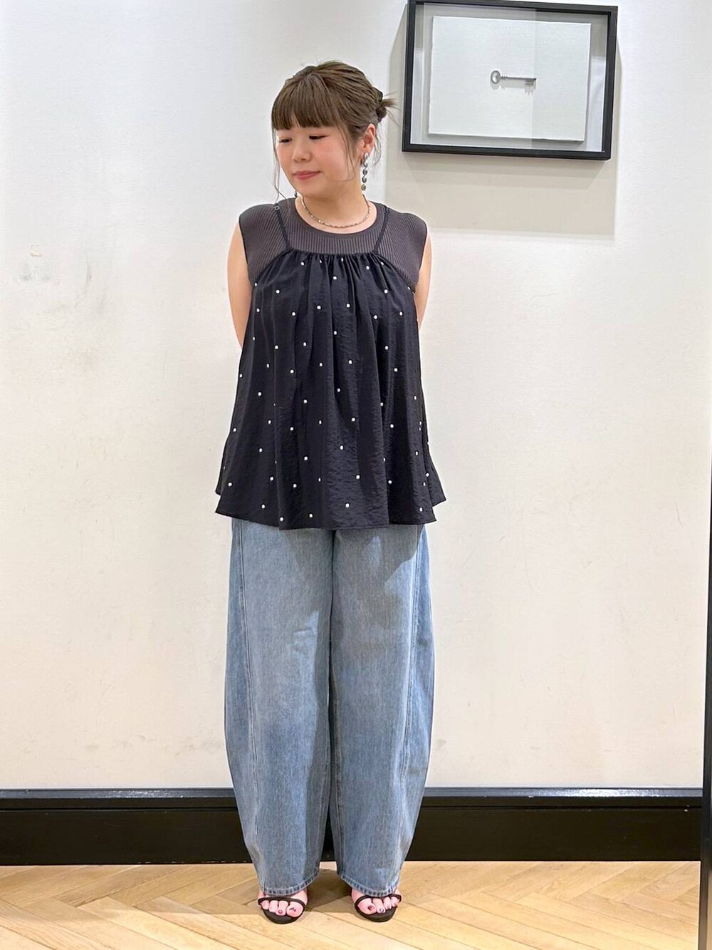 ブルー系のデニムパンツ、ブラウン系のサンダル、グレー系のタンクトップを着用したレディースの夏コーディネートの3枚目の写真