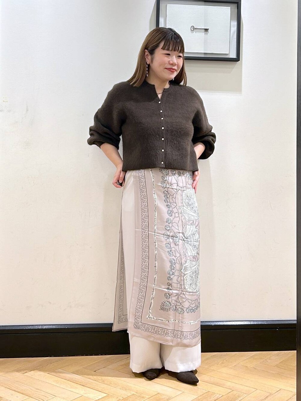 ブラウン系のカーディガン/ボレロ、ホワイト系のスラックス、ブラウン系のパンプスを着用したレディースの秋コーディネートの4枚目の写真