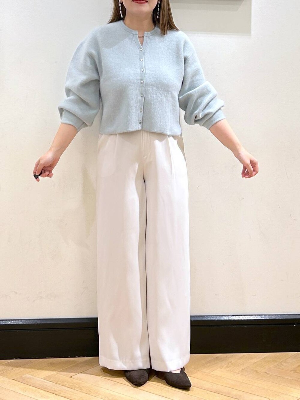 グリーン系のカーディガン/ボレロ、ホワイト系のスラックス、ブラウン系のパンプスを着用したレディースの秋コーディネートの4枚目の写真