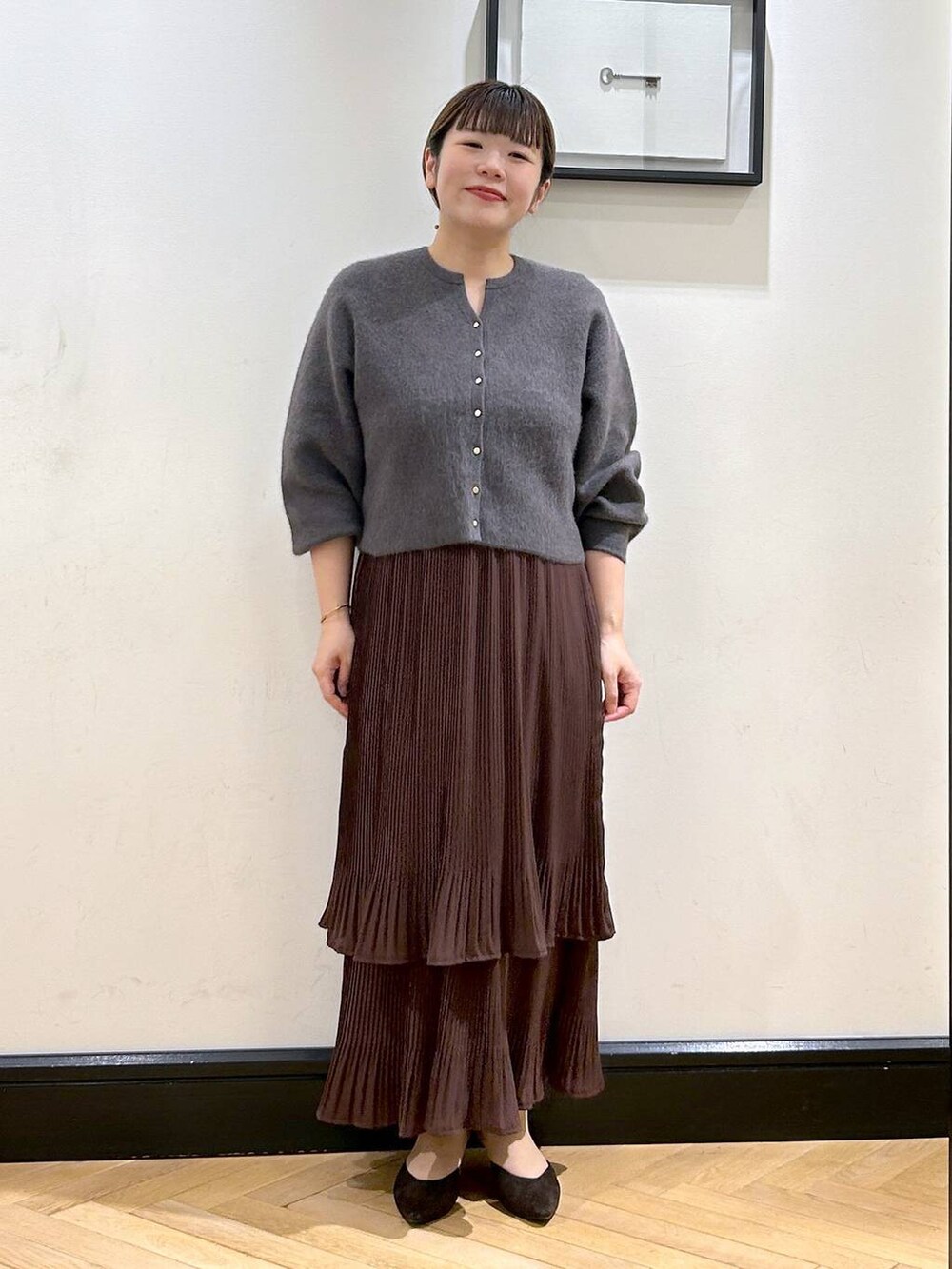 ブラウン系のスカート、グレー系のカーディガン/ボレロ、ブラウン系のパンプスを着用したレディースの秋コーディネートの2枚目の写真