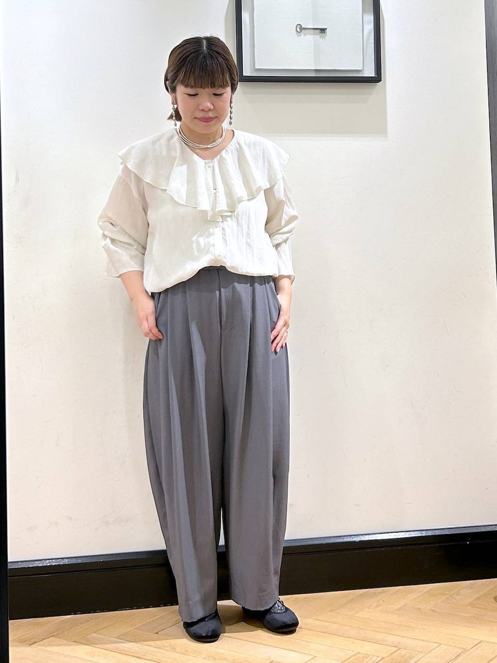 グレー系のスラックス、ブラック系のバレエシューズ、ホワイト系のシャツ/ブラウスを着用したレディースの秋コーディネートの5枚目の写真