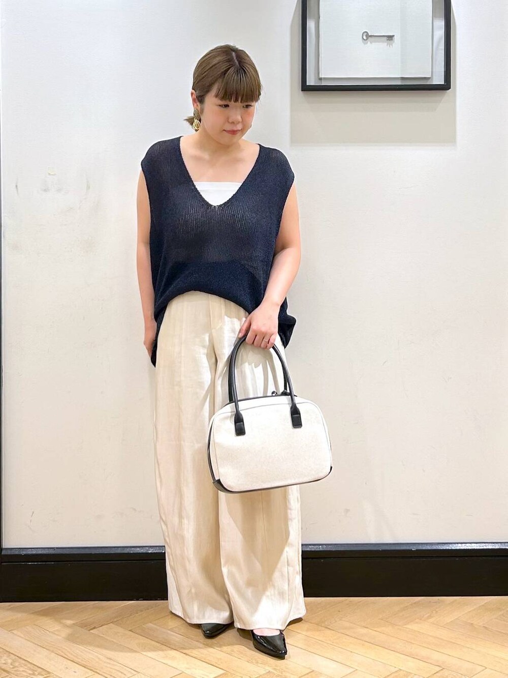 ブラック系のパンプス、ホワイト系のタンクトップ、ブラック系のボストンバッグを着用したレディースの夏コーディネートの2枚目の写真