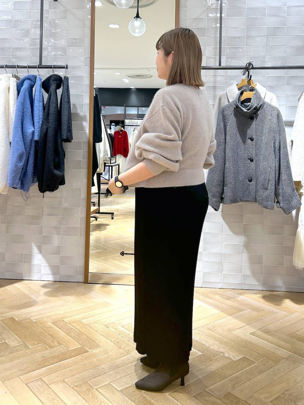 ブラック系のスカート、ベージュ系のカーディガン/ボレロ、ブラウン系のブーツを着用したレディースの秋コーディネートの5枚目の写真