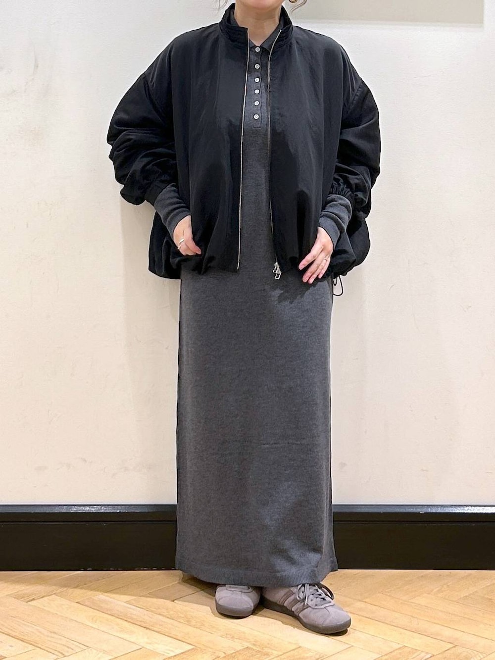 グレー系のスニーカー、グレー系のワンピース、ブラック系のブルゾンを着用したレディースの秋コーディネートの5枚目の写真