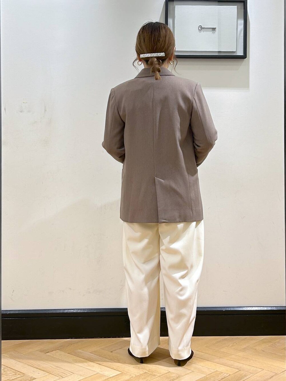 ホワイト系のスラックス、ブラウン系のパンプス、ブラック系のショルダーバッグを着用したレディースの秋コーディネートの8枚目の写真