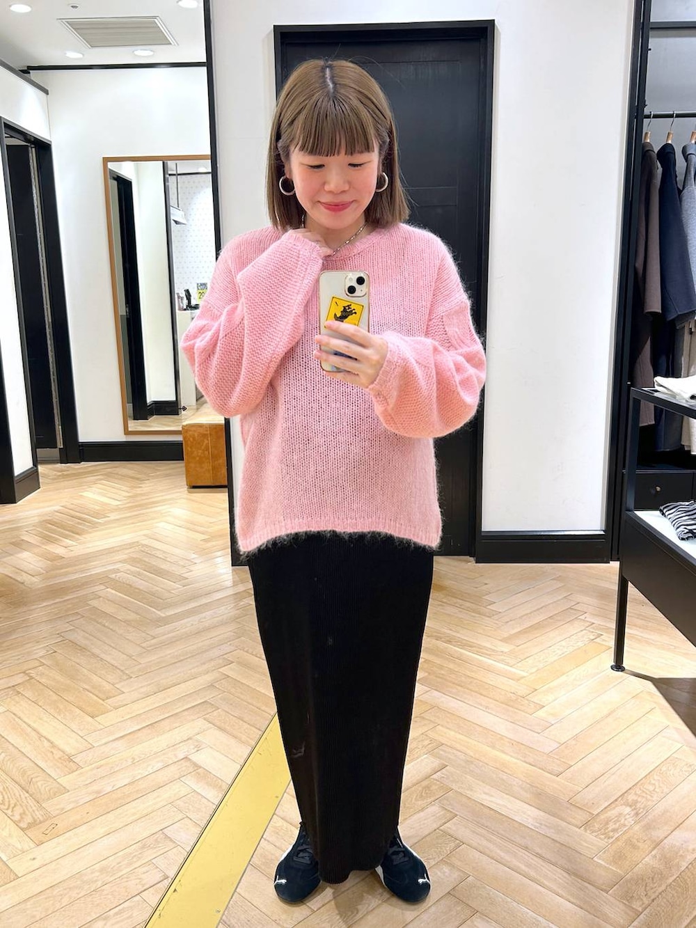 ブラック系のスニーカー、ブラック系のスカート、ピンク系のニット/セーターを着用したレディースの秋コーディネートの2枚目の写真