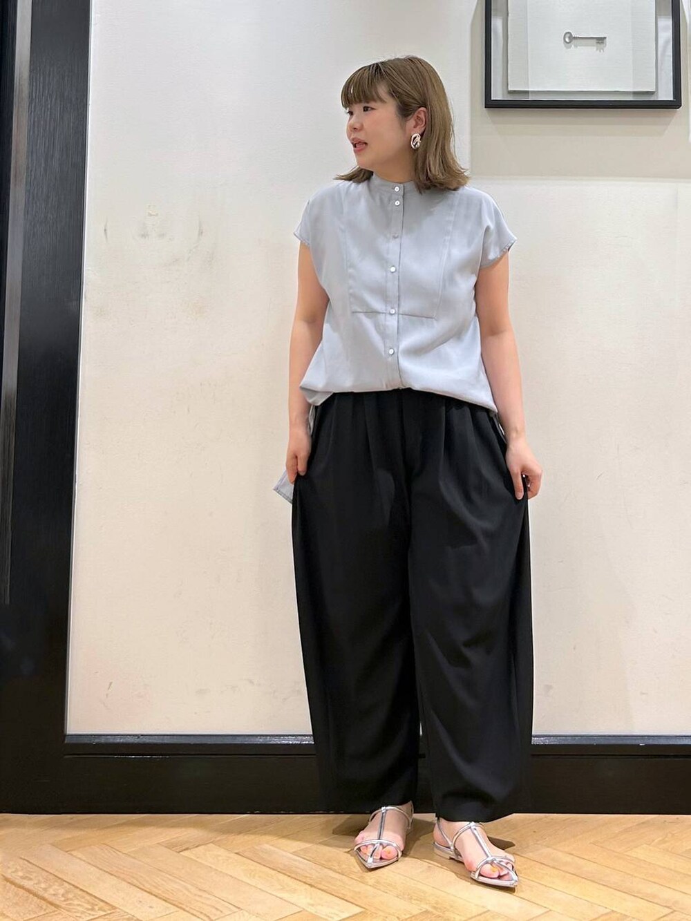 シルバー系のサンダル、ブラック系のスラックス、ブラック系のショルダーバッグを着用したレディースの夏コーディネートの4枚目の写真