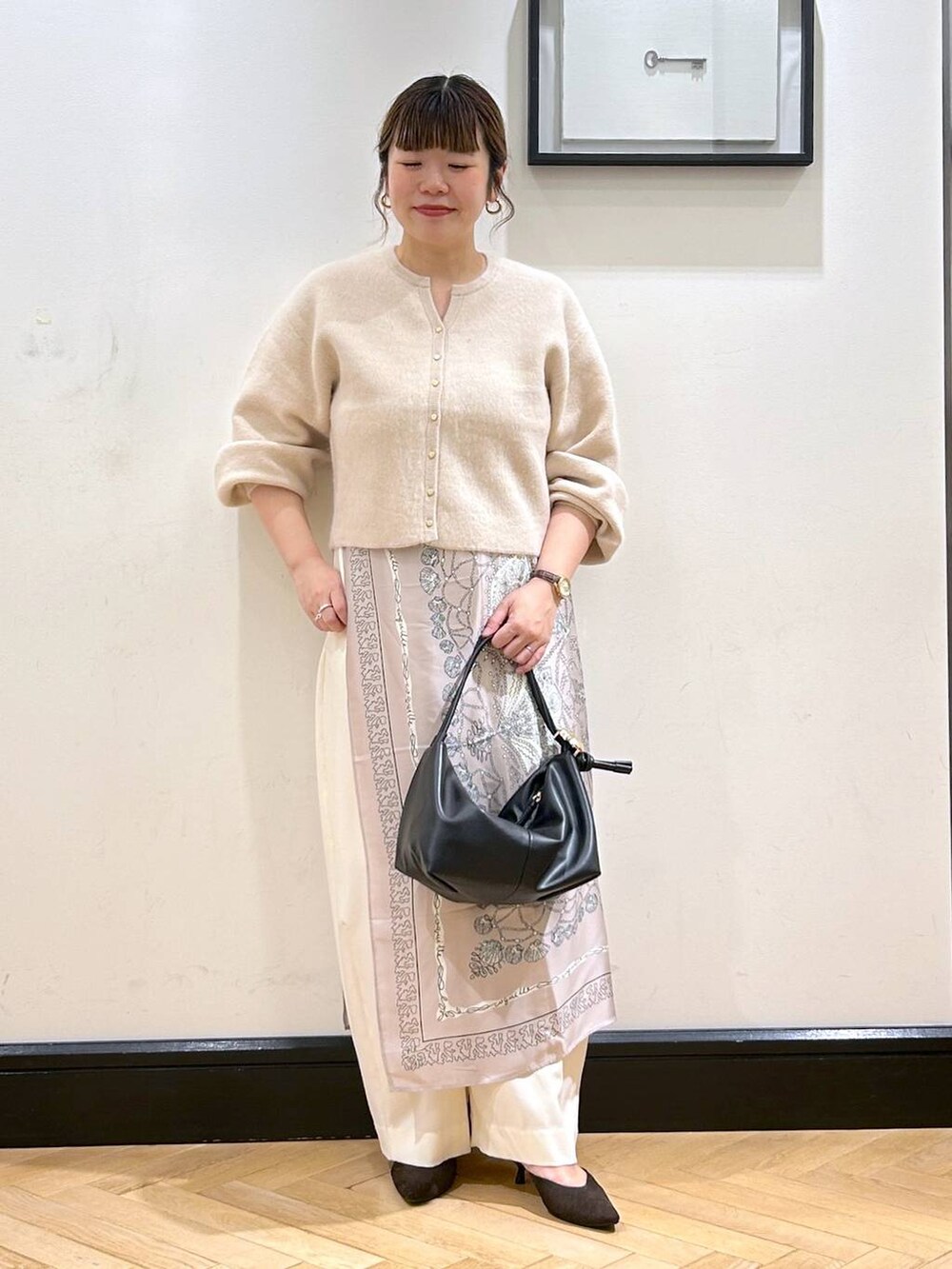 ホワイト系のスラックス、ホワイト系のカーディガン/ボレロ、ブラウン系のパンプスを着用したレディースの秋コーディネートの3枚目の写真