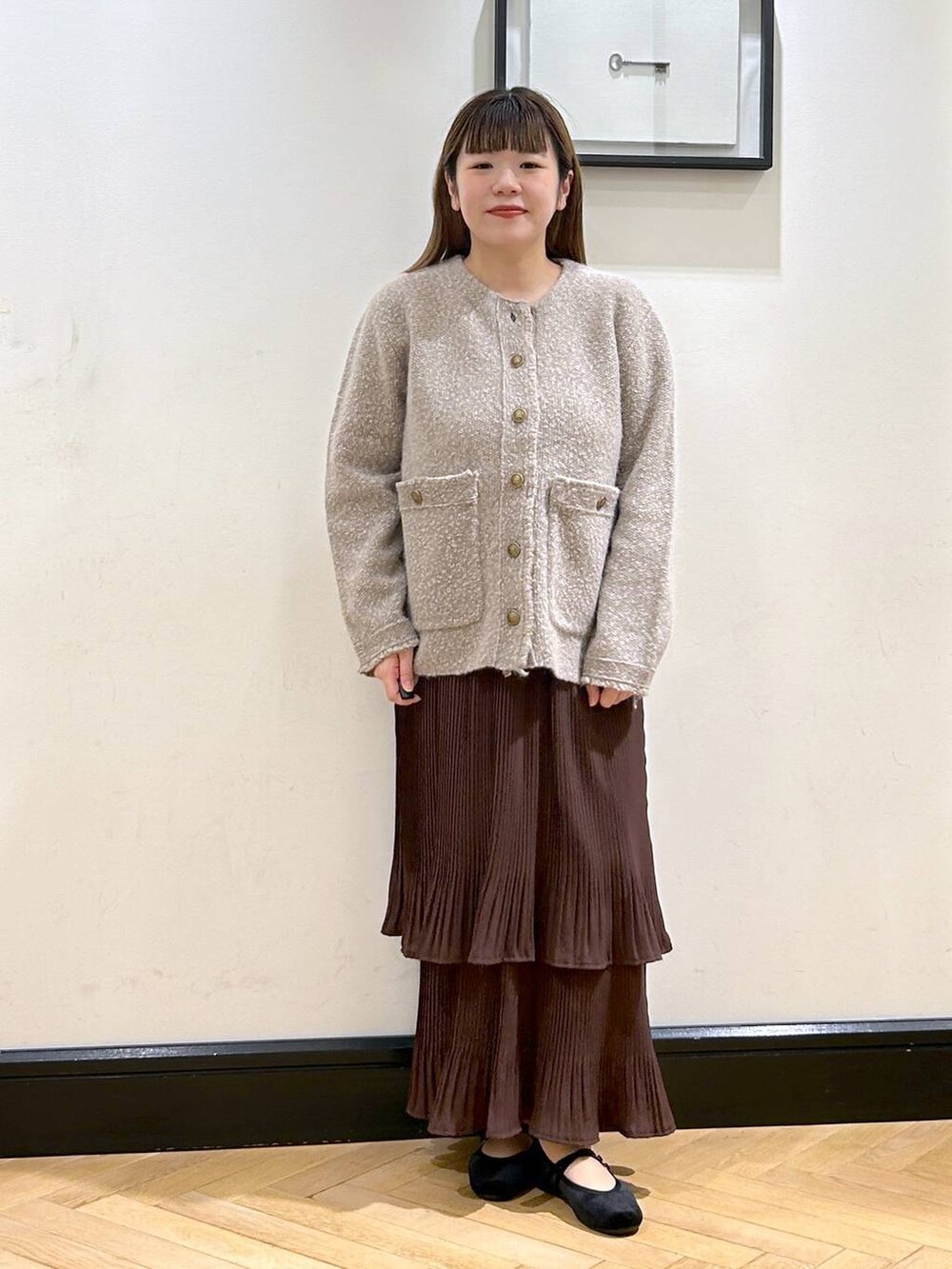 ブラウン系のスカート、ベージュ系のカーディガン/ボレロ、ブラック系のバレエシューズを着用したレディースの秋コーディネートの4枚目の写真