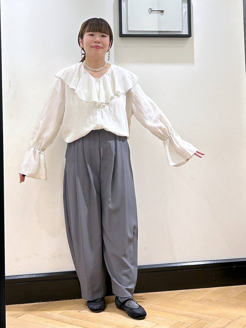 グレー系のスラックス、ブラック系のバレエシューズ、ホワイト系のシャツ/ブラウスを着用したレディースの秋コーディネートの3枚目の写真