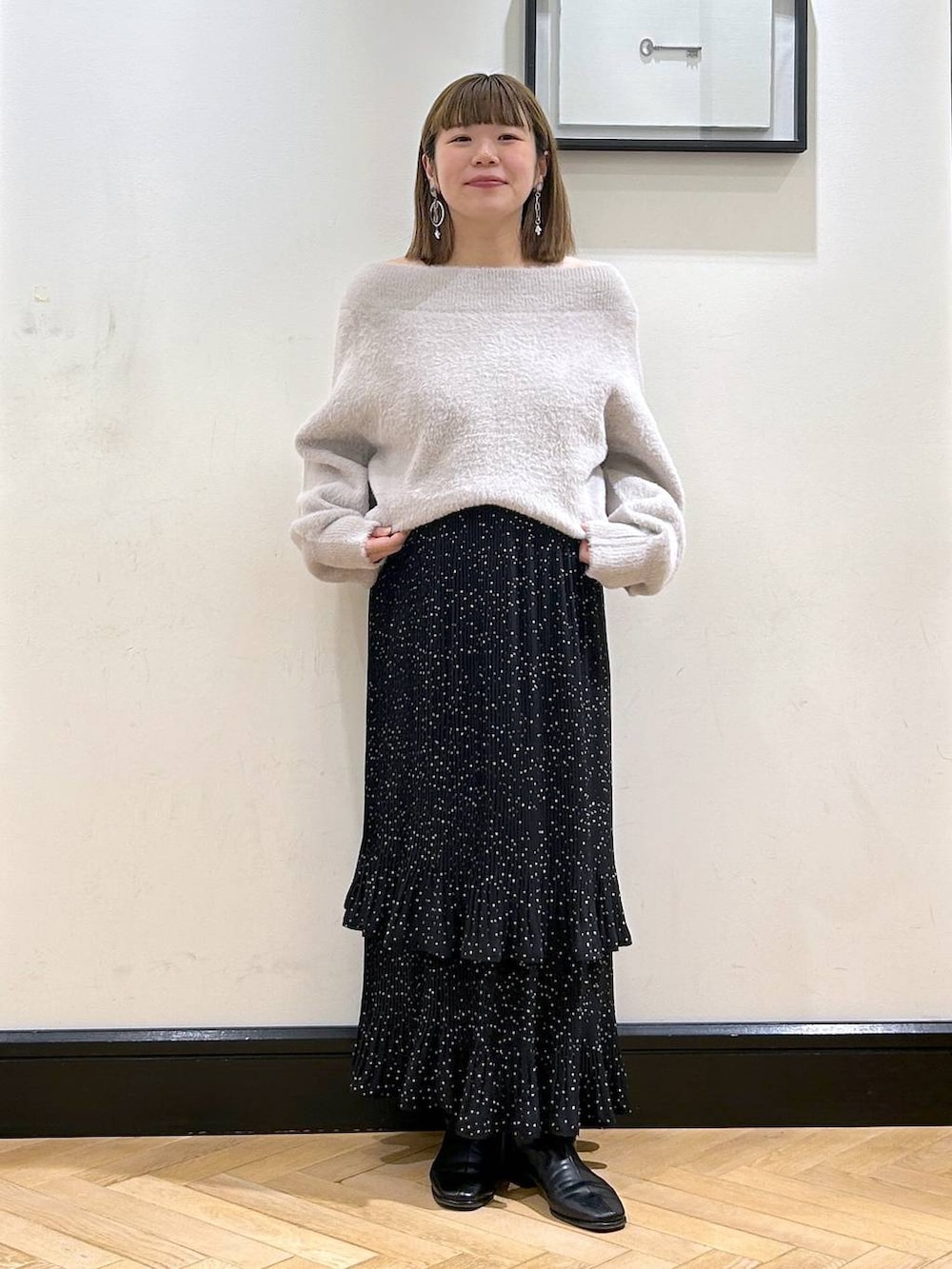 グレー系のスカート、ブラック系のブーツ、グレー系のニット/セーターを着用したレディースの冬コーディネートの2枚目の写真