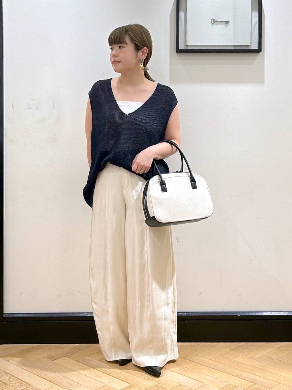 ブラック系のパンプス、ホワイト系のタンクトップ、ブラック系のボストンバッグを着用したレディースの夏コーディネートの4枚目の写真