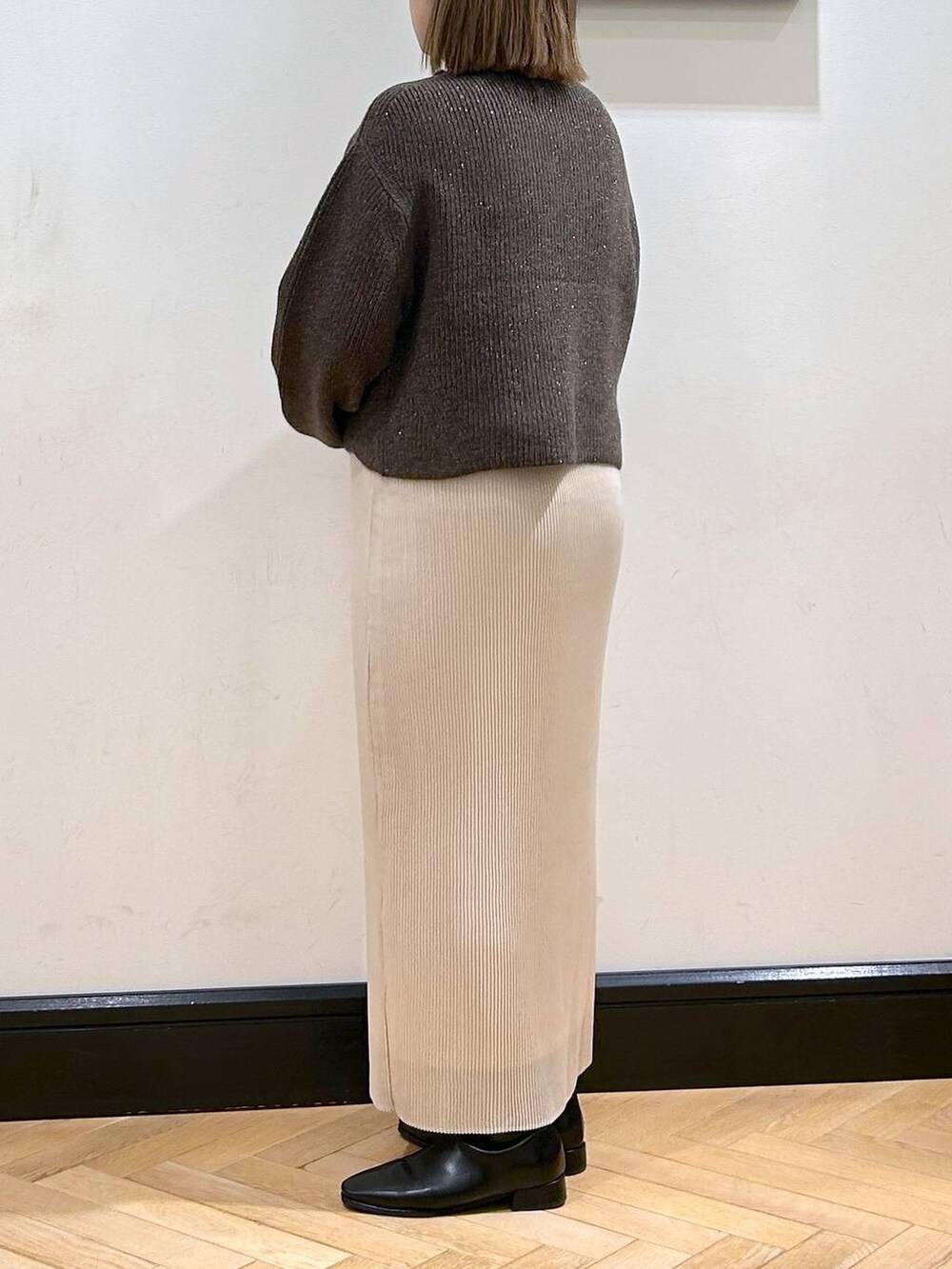 ブラウン系のニット/セーター、ホワイト系のスカート、ブラック系のブーツを着用したレディースの秋コーディネートの7枚目の写真