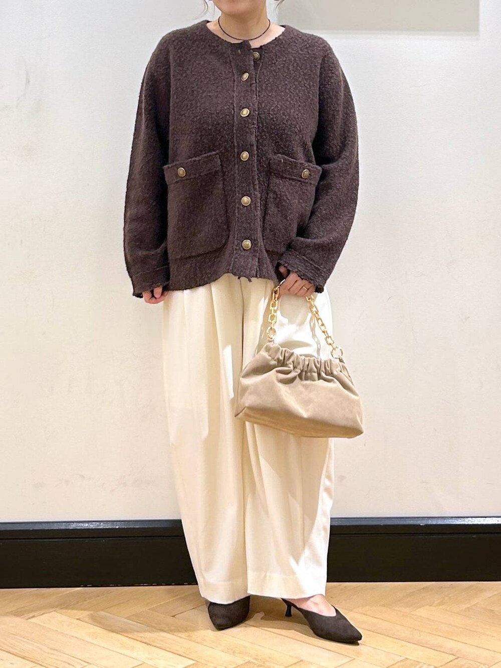 ホワイト系のスラックス、ブラウン系のパンプス、ベージュ系のショルダーバッグを着用したレディースの秋コーディネートの4枚目の写真