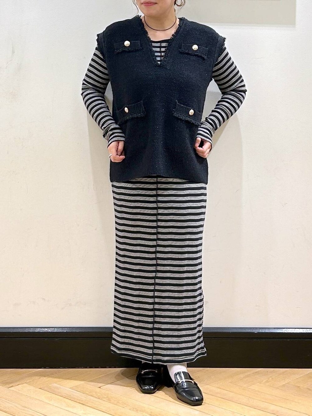 ブルー系のベスト、ブラック系のローファー、ベージュ系のショルダーバッグを着用したレディースの秋コーディネートの4枚目の写真