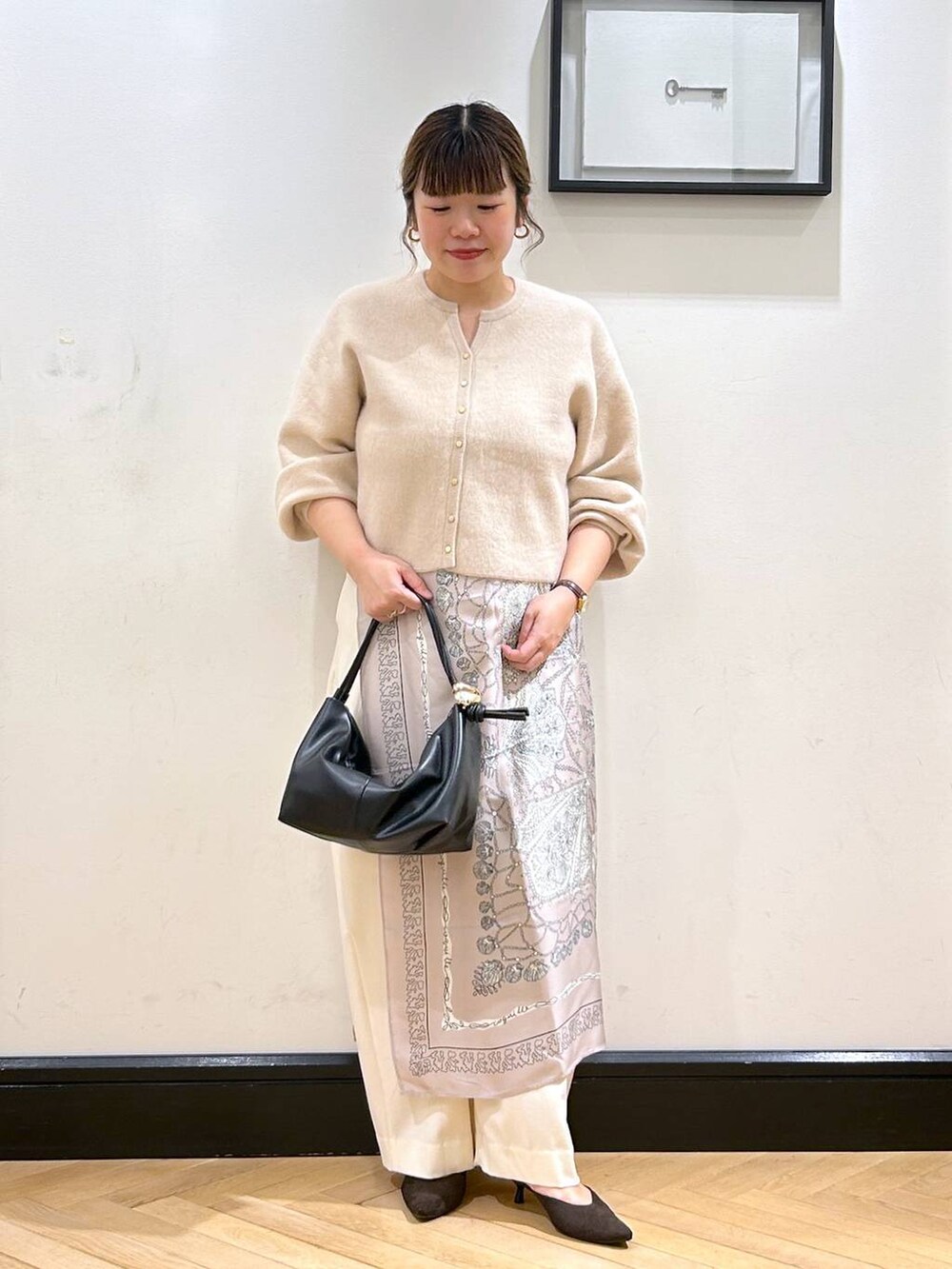 ホワイト系のスラックス、ホワイト系のカーディガン/ボレロ、ブラウン系のパンプスを着用したレディースの秋コーディネートの2枚目の写真
