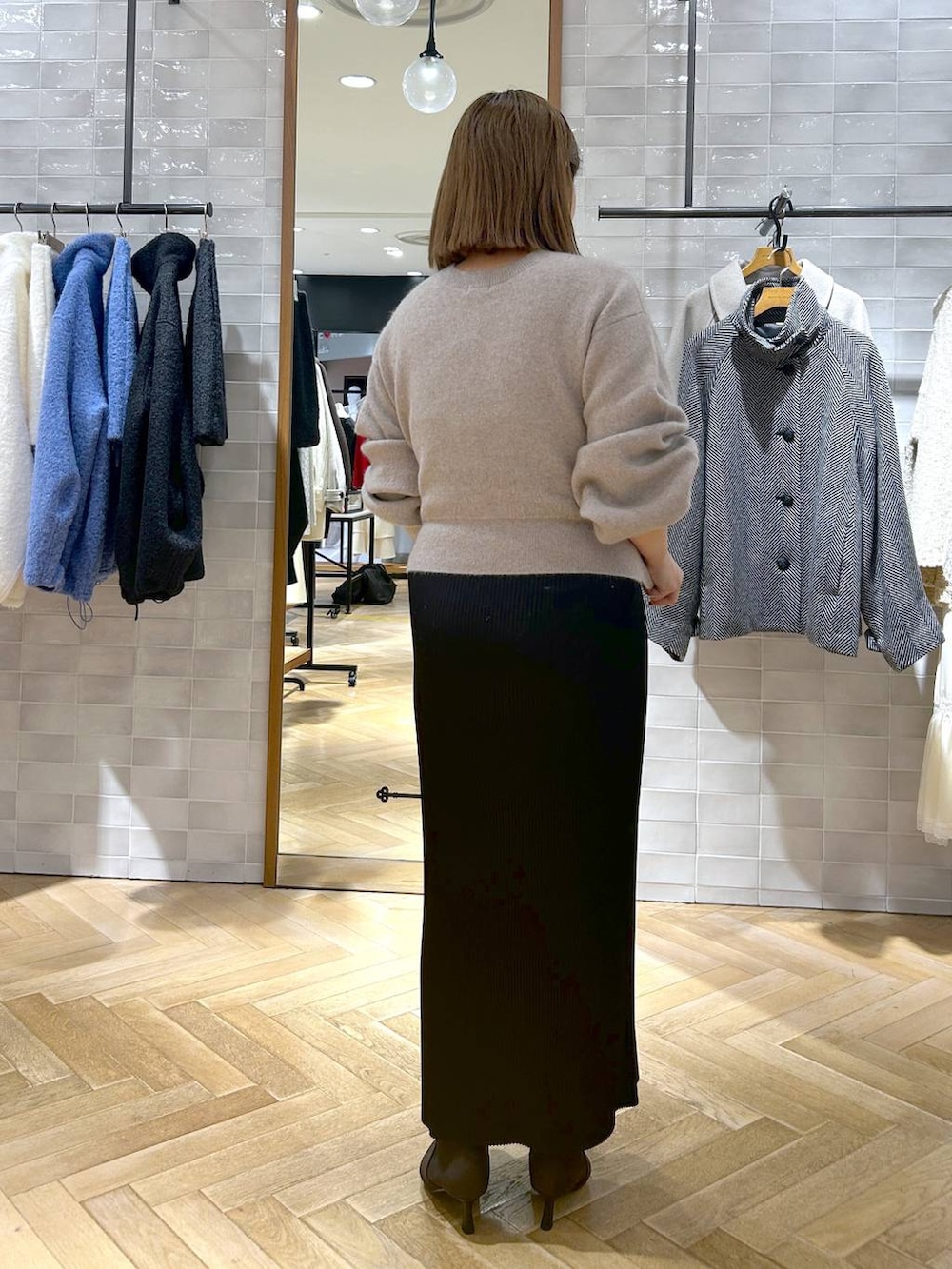 ブラック系のスカート、ベージュ系のカーディガン/ボレロ、ブラウン系のブーツを着用したレディースの秋コーディネートの6枚目の写真