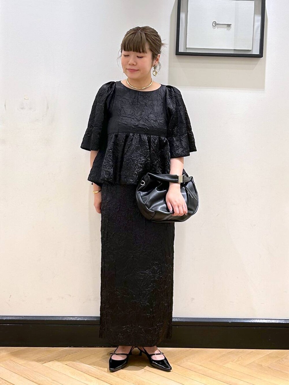ブラック系のハンドバッグ、ブラック系のパンプス、ブラック系のワンピースを着用したレディースの夏コーディネートの4枚目の写真